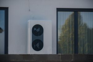 Pompe à chaleur extérieure moderne avec deux ventilateurs grandes, installée à côté d'une fenêtre sur le mur d'une maison