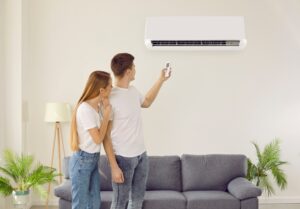 Deux locataires allumant un revitalisant dans le salon respirant de l'air frais. Les locataires d'hommes et de femmes utilisent des dispositifs de condition à la maison. Ventilation intérieure et technologie moderne.