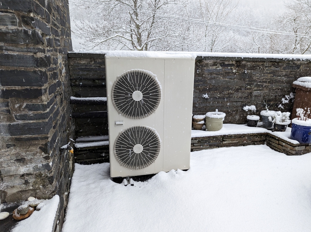 Vue enneigée d'une unité extérieure pour une pompe à chaleur à source d'air.