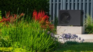Pompe à chaleur installée près d'une piscine entourée de plantes décoratives.