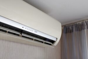 La main d'un homme allume un climatiseur à l'aide d'une télécommande dans un appartement ou une maison. Technologies modernes de climatisation. Mise au point sélective.