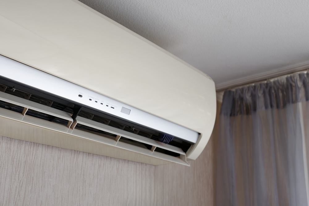 La main d'un homme allume un climatiseur à l'aide d'une télécommande dans un appartement ou une maison. Technologies modernes de climatisation. Mise au point sélective.