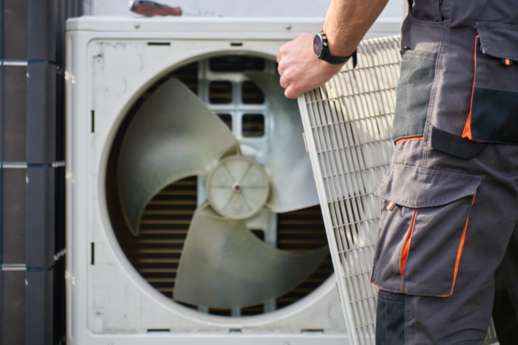 technician,removing,front,cover,grille,from,outdoor,heat,pump,unit